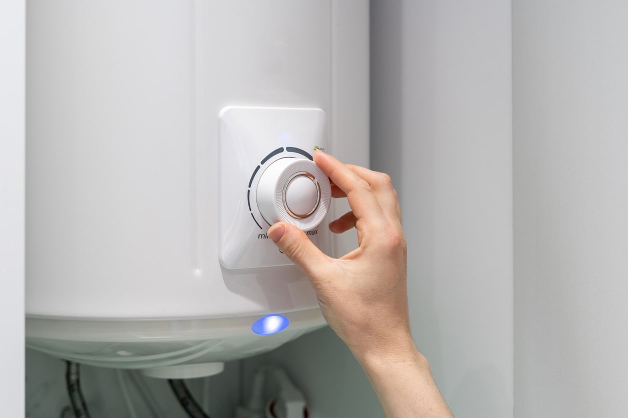 Woman's hand adjusting the temperature on a residential boiler 