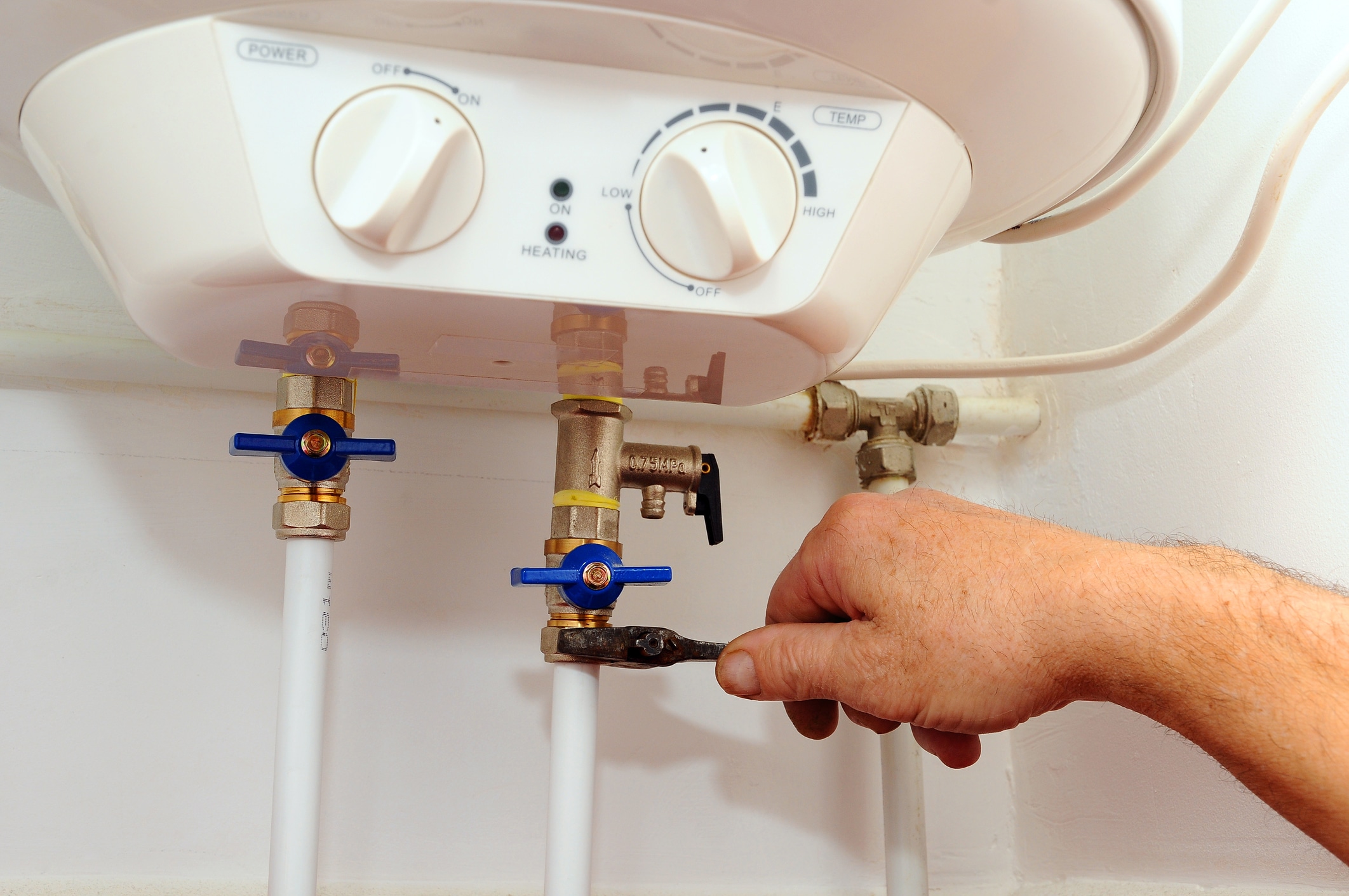 Man's hand performing a service on a tankless water heater 